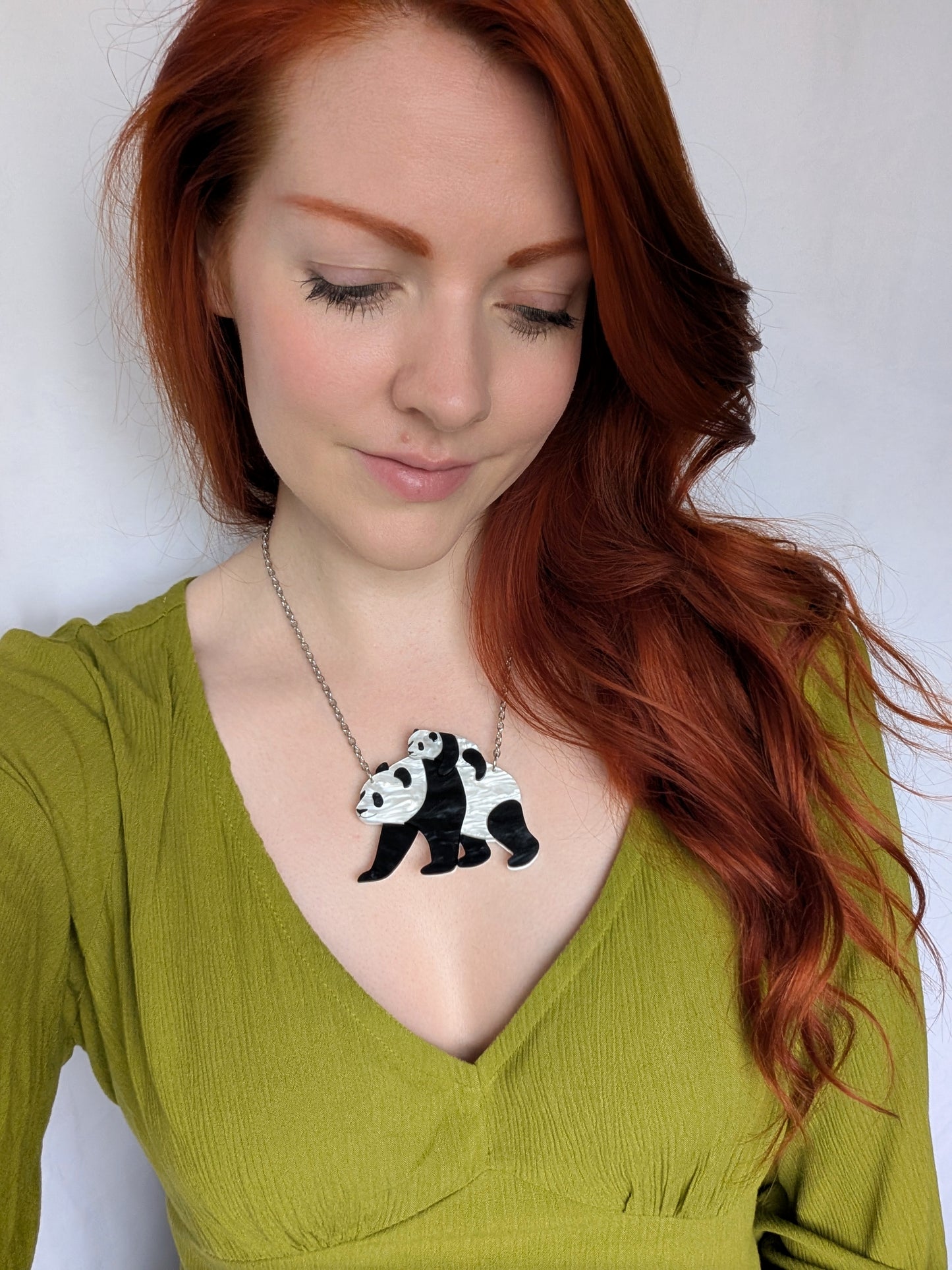 Woman wearing a panda necklace against a plain background