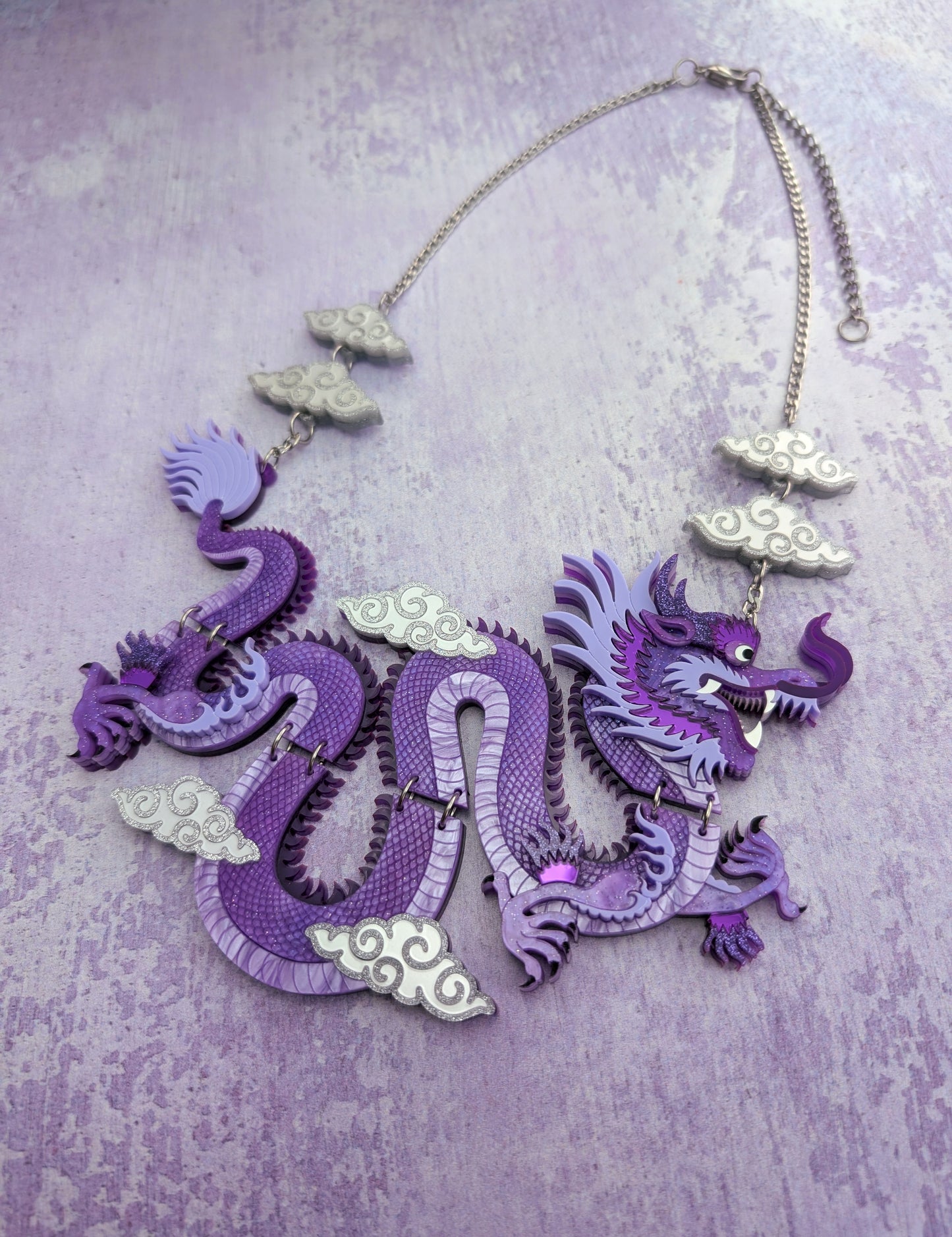 Laser cut handmade acrylic rock the Panda purple dragon necklace on a textured purple background