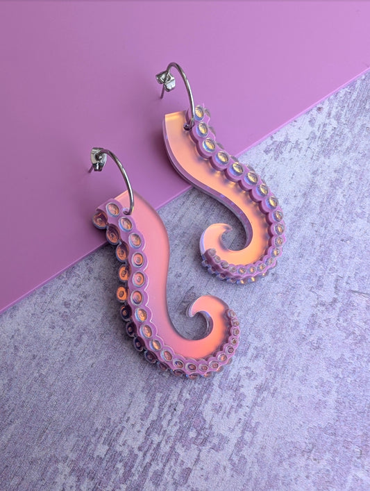 Iridescent lilac octopus tentacle earrings on a pink and gray background