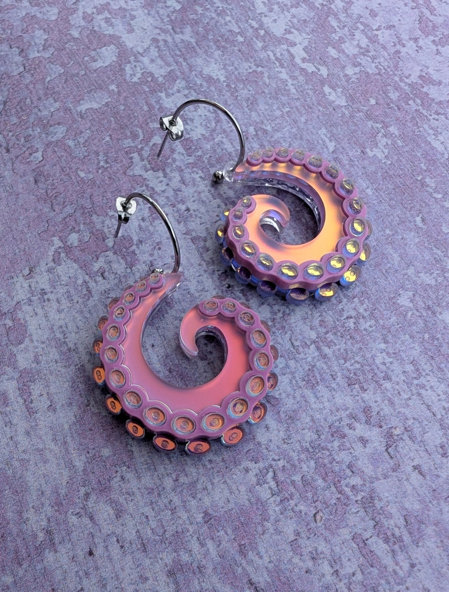 Pair of octopus tentacle inspired earrings on a textured purple background